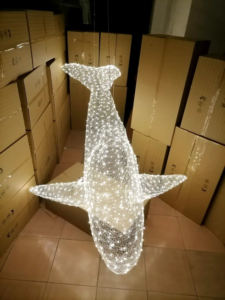 Hand-woven whale light sculpture, lit, ready for packing